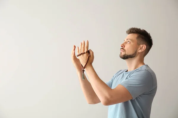 Религиозный человек молится на светлом фоне — стоковое фото