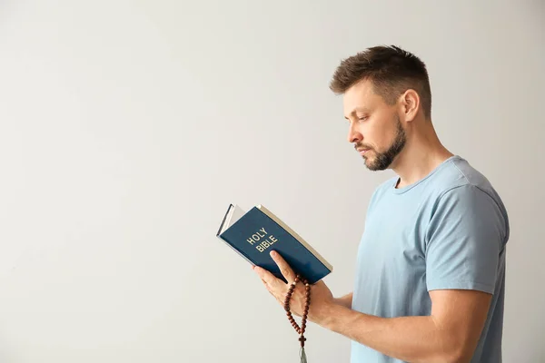 Religious man reading Bible on light background — Stock Photo, Image