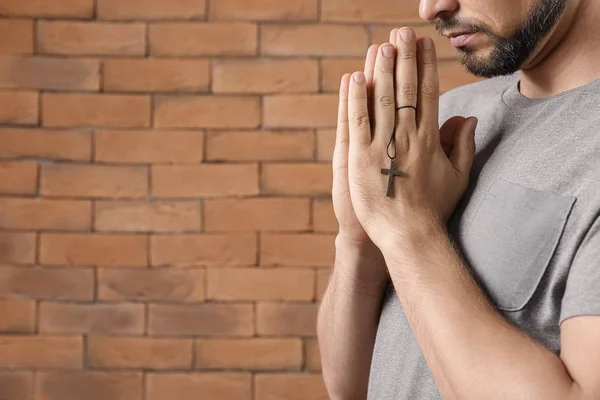 Religious man praying against brick wall — Stock Photo, Image