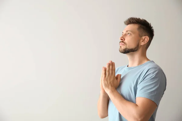 Religious man praying on light background — Stock Photo, Image