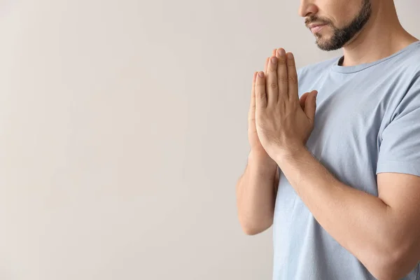 Religious man praying on light background — Stock Photo, Image