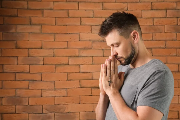 Religious man praying against brick wall — Stock Photo, Image
