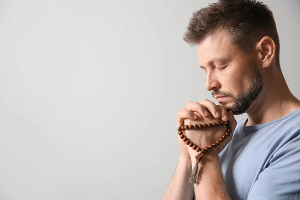 Religious man praying on light background — Stock Photo, Image