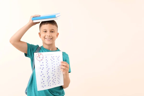 Niño feliz con hoja de respuesta para la prueba de la escuela en fondo claro — Foto de Stock