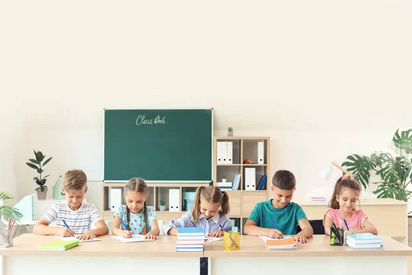 Alunos passando no teste escolar em sala de aula — Fotografia de Stock