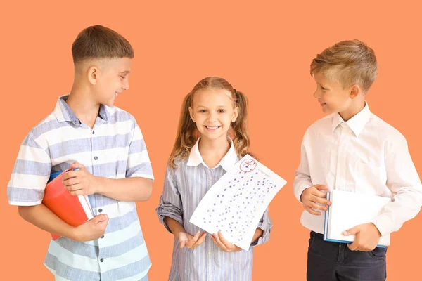 Щасливі діти з листом відповіді на шкільний тест на кольоровому фоні — стокове фото