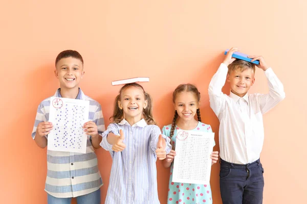 Enfants heureux avec des feuilles de réponse pour le test scolaire sur fond de couleur — Photo