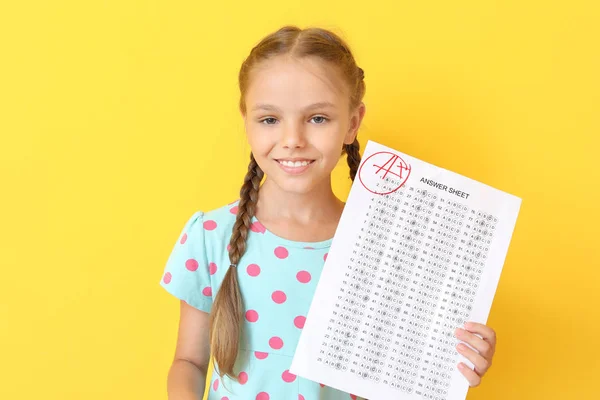 色の背景に学校のテストのための解答シートを持つ幸せな女の子 — ストック写真