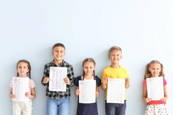 Bambini con fogli di risposta per test scolastici su sfondo di colore chiaro — Foto Stock