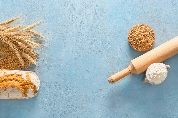 Wheat grains with flour and bread on color background — Stock Photo, Image