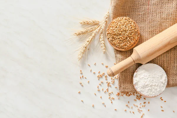 Rolling pin with wheat grains and flour on light background — Stock Photo, Image