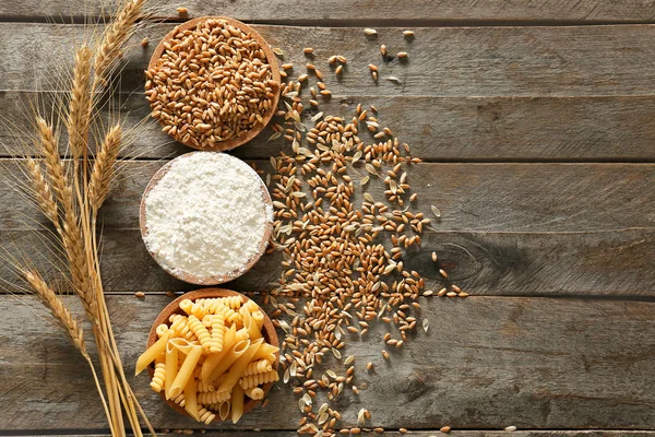 Raw pasta with wheat flour and grains on wooden table — Stock Photo, Image