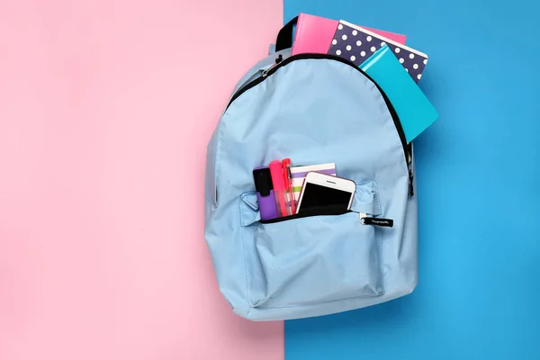 School backpack with stationery on color background — Stock Photo, Image