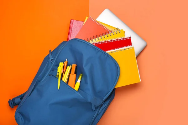 Mochila escolar con papelería sobre fondo de color — Foto de Stock