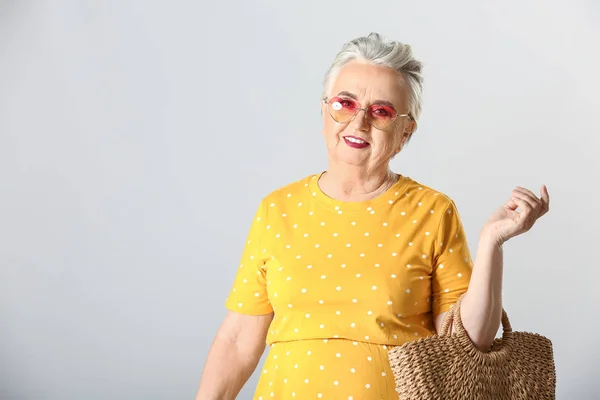 Mulher idosa elegante em fundo cinza — Fotografia de Stock