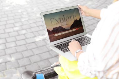Dizüstü bilgisayar ziyaret seyahat acentesi web sitesi ile Kadın bankta açık havada otururken