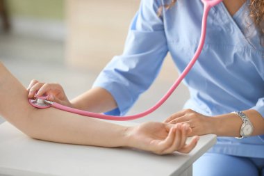 Klinikte genç kadının nabzını ölçen doktor