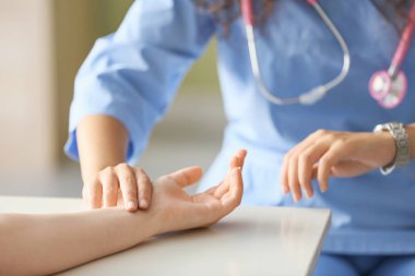 Klinikte genç kadının nabzını ölçen doktor