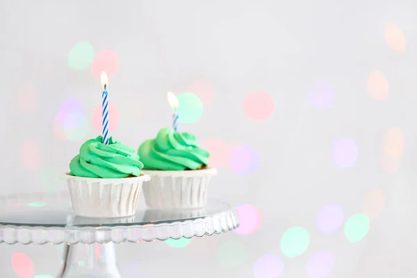 Gustosi cupcake di compleanno in stand contro le luci sfocate — Foto Stock