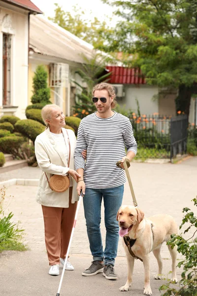 Blind young man with guide dog and mother outdoors