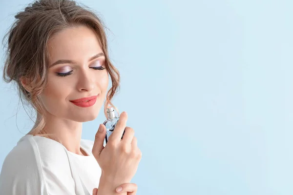 Beautiful young woman with bottle of perfume on color background — Stock Photo, Image