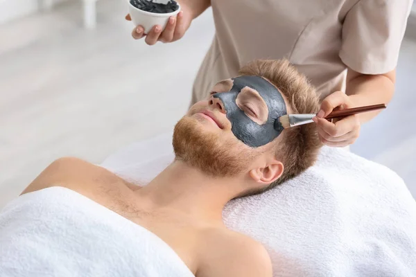 Cosmetologist applying mask on man's face in spa salon — Stock Photo, Image