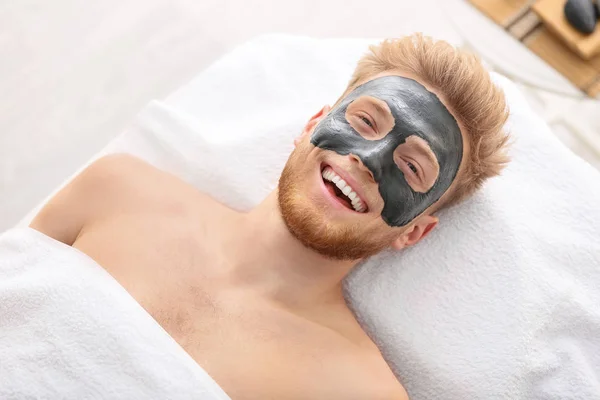 Bel homme avec masque sur le visage dans le salon de spa — Photo