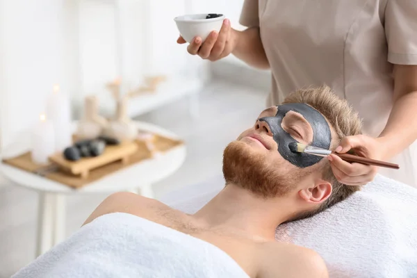 Косметолог надевает маску на лицо человека в салон красоты — стоковое фото