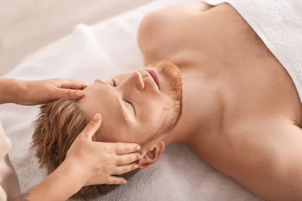Bonito jovem recebendo massagem no salão de spa — Fotografia de Stock