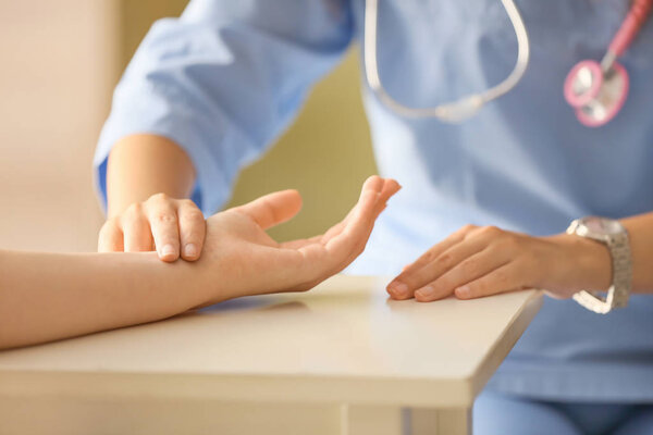 Doctor measuring pulse of young woman in clinic