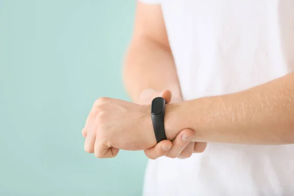 Man with fitness tracker checking his pulse on color background, closeup — Stock Photo, Image