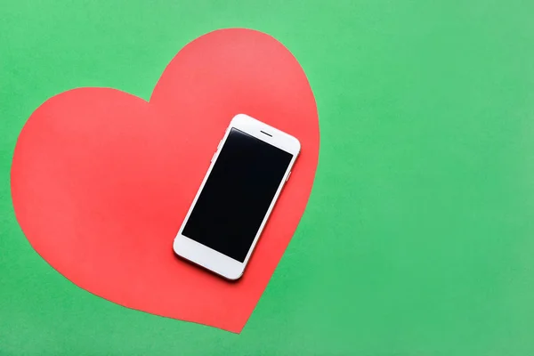 Современный мобильный телефон и бумажное сердце на цветном фоне — стоковое фото