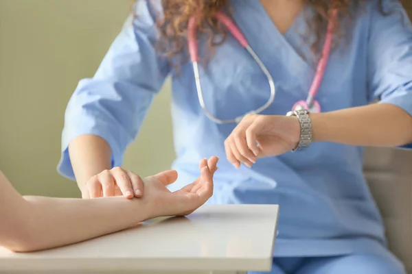 Doctor measuring pulse of young woman in clinic — Stock Photo, Image