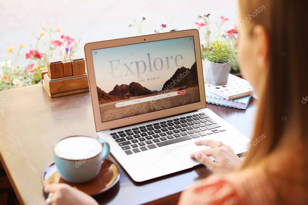 Woman with laptop visiting travel agency website while sitting in cafe