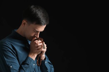 Dindar adam karanlık arka planda Tanrı 'ya dua ediyor.