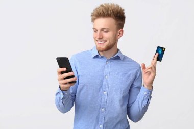 Beyaz arka planda kredi kartı ve cep telefonu ile Mutlu işadamı