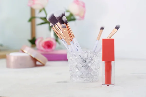 Lipstick and makeup brushes on dressing table — Stock Photo, Image