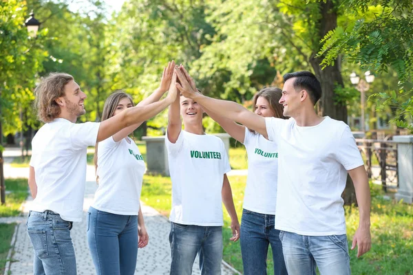 Grupo de voluntarios poniendo las manos juntas al aire libre — Foto de Stock