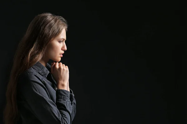 Religious young woman praying to God on dark background — Stock Photo, Image