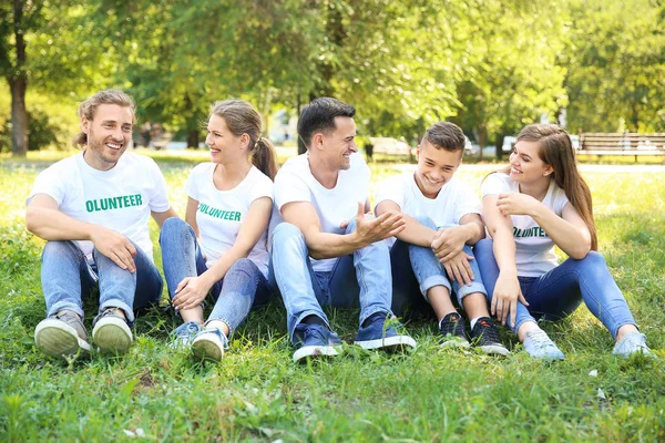 Az önkéntesek csoportja ül a zöld fű szabadban — Stock Fotó