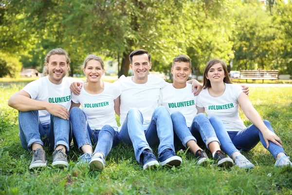 Grupo de voluntários sentados na grama verde ao ar livre — Fotografia de Stock