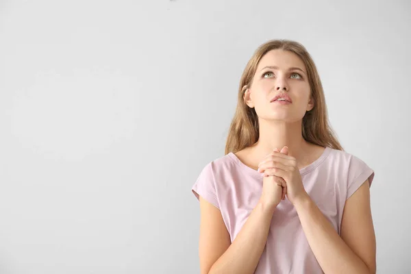 Religiosa joven rezando a Dios sobre fondo claro —  Fotos de Stock