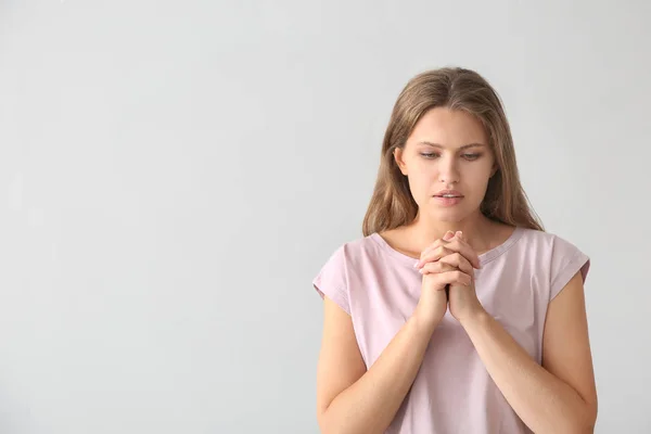 Vallási fiatal asszony imádkozott Istenhez a világos háttér — Stock Fotó