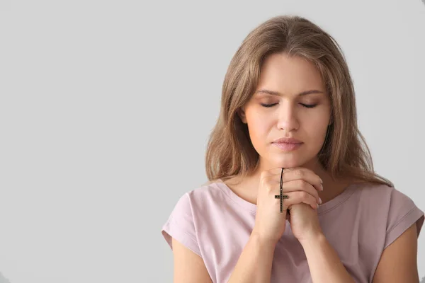 Religious young woman praying to God on light background — Stock Photo, Image