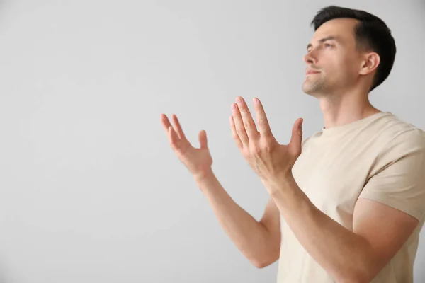 Religiöser Mann betet zu Gott auf hellem Hintergrund — Stockfoto