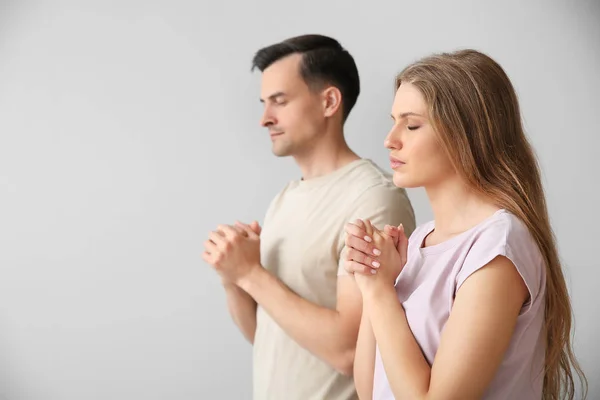 Religious couple praying to God on light background