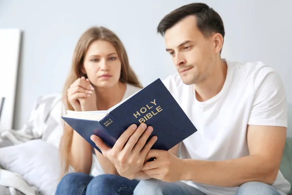 Religious couple reading Bible at home