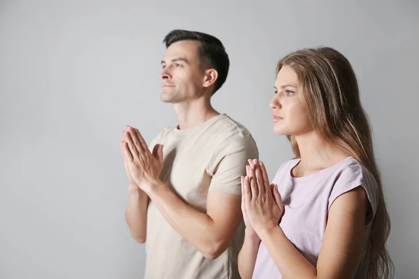 Casal religioso orando a Deus em fundo cinza — Fotografia de Stock