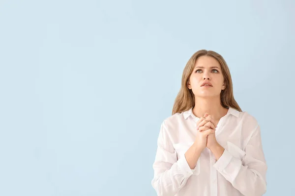 Релігійна молода жінка молилася до Бога на фоні світлого кольору — стокове фото