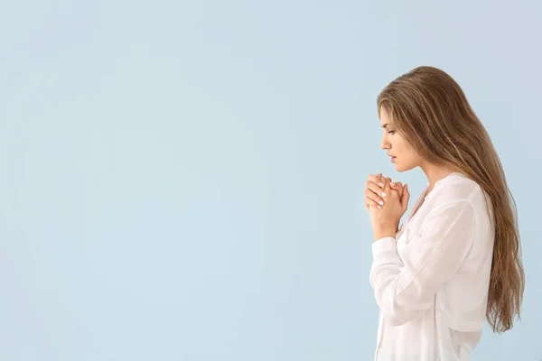 Religiosa jovem orando a Deus em fundo de cor clara — Fotografia de Stock